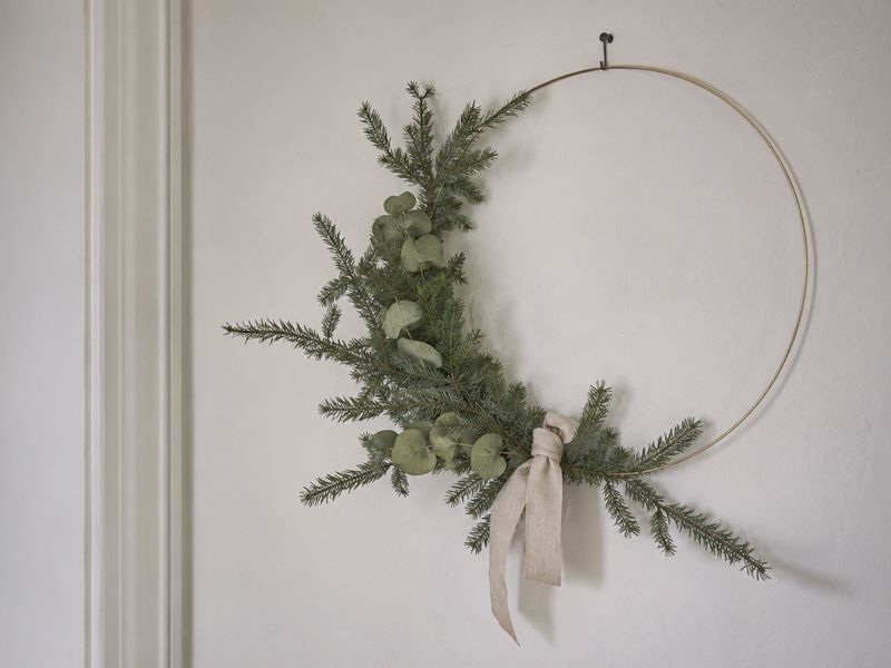 Minimalistyczny wieniec świąteczny DIY - lekki wieniec z cienkiej obręczy, igliwia i eukaliptusa zawieszony na jasnej ścianie